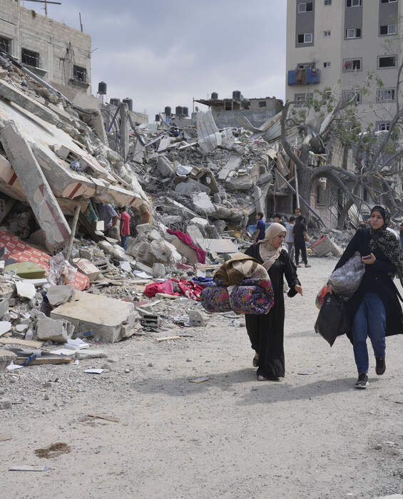 Destruction in Gaza - urgent call for aid Palestinian women walk past destroyed buildings in Nuseirat, Gaza - urgent need for humanitarian aid.